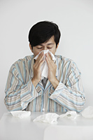 Young man blowing his nose, sneezing - Yukmin