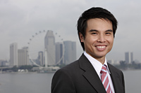 Chinese man in suit standing in front of city skyline, smiling - Yukmin