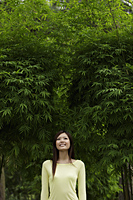 Young woman smiling in front of bamboo trees - Yukmin