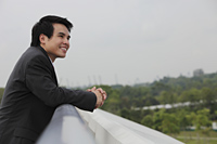 Man wearing suit leaning on wall and looking at view - Yukmin