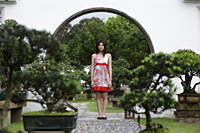 Young woman standing with bonsai trees - Yukmin