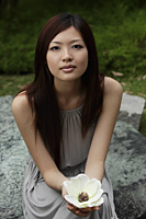 Young woman holding white flower and looking at camera - Yukmin