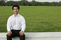 Man in white shirt sitting on grass with eyes close - Yukmin