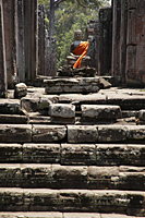 Stone carving of Buddha wrapped in orange robe. Angkor Wat, Cambodia - Alex Mares-Manton