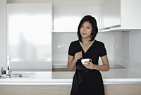 young woman holding mug in her kitchen - Yukmin