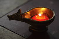 Lit candle in bronze cow dish - Alex Mares-Manton