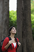 Mid shot of woman wearing back pack and looking up at trees. - Alex Mares-Manton