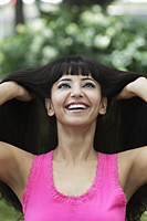 Head shot of woman looking up and smiling with hands in her hair - Alex Mares-Manton