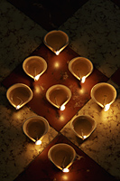 Lit oil lamps in a triangle shape on floor - Alex Mares-Manton