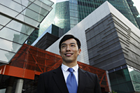 Young businessman smiling in front of modern buildings - Yukmin