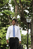 Indian man walking outside holding briefcase and smiling - Alex Mares-Manton