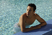 Young man resting on side of swimming pool - Yukmin