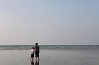 Back view of father and son holding hands and looking at the sea - Yukmin