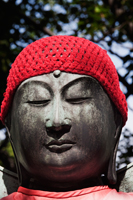 Buddhist stone statue wearing a red hat. Asakusa Kannon Temple, Japan - Travelasia
