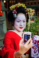 Geisha taking a photo of herself with her phone. - Travelasia