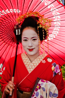 Head shot of Geisha wearing red Kimono and holding red umbrella - Travelasia