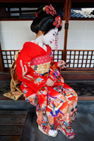 Geisha in red Kimono looking at mobile phone - Travelasia