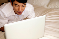 man laying on bed working on laptop - Yukmin