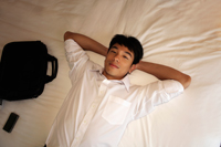man laying on bed with hands behind his head. - Yukmin