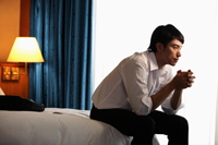 Profile of man sitting on the bed in hotel room - Yukmin