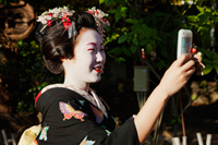 Japanese woman in traditional clothes taking a photo - Travelasia