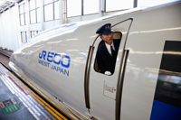 Train conductor leaning out of window of bullet train (Shinkansen), Japan - Travelasia