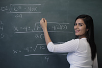 Young woman writing math equation on chalk board and smiling - Alex Mares-Manton