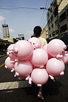 Woman walking with pink pig balloons down the street of Shanghai, China - Yukmin