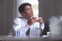 Male executive holding coffee cup in cafe, thoughtful expression - Alex Microstock02