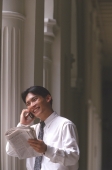 Male executive talking on cellular phone holding newspaper, smiling - Alex Microstock02