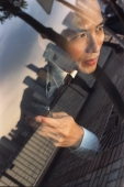Male executive with cellular phone, skyline reflected in car window - Jade Lee
