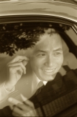 Male executive using cellular phone hands-free set in car, smiling - Jade Lee