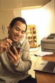 Man at home talking on telephone, holding palmtop - Jade Lee