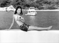 Teenage girl in bikini using cellular phone, boat in background - Jade Lee