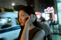 Female executive talking on cellular phone with neon in background - Jade Lee