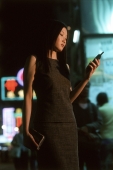 Female executive dialing cellular phone with neon in background - Jade Lee