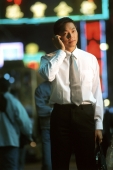 Male executive talking on cellular phone, neon in background - Jade Lee