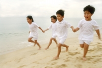 Children in white clothing, holding hands, running along the beach - Alex Microstock02