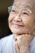 Mature woman with glasses, resting chin on fist, smiling - Mary Grace Long