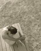 Woman sitting on wooden deck with water below - Jack Hollingsworth