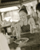 Woman eating at restaurant, smiling - Jack Hollingsworth