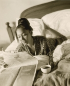 Woman in bed reading newspaper, drinking coffee - Jack Hollingsworth