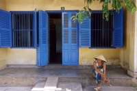 Vietnam, Danang, woman sitting in front of house. - Steve Raymer