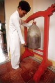 Vietnam, Tay Ninh, Cao Dai worshipper strike bell in Cao Dai Great Temple. - Steve Raymer