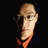 Male executive wearing glasses, portrait, black background - Jade Lee