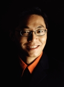 Male executive smiling, portrait, black background - Jade Lee