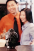 Couple in antique store, statue of Buddha in foreground - Jade Lee