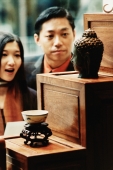 Couple looking in antique store window, Buddha statue in foreground - Jade Lee