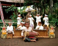 Indonesia, Bali, man playing hand drum, young boys in traditional costume dancing - Jack Hollingsworth