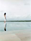 Woman walking on water's edge with reflection. - Jack Hollingsworth
